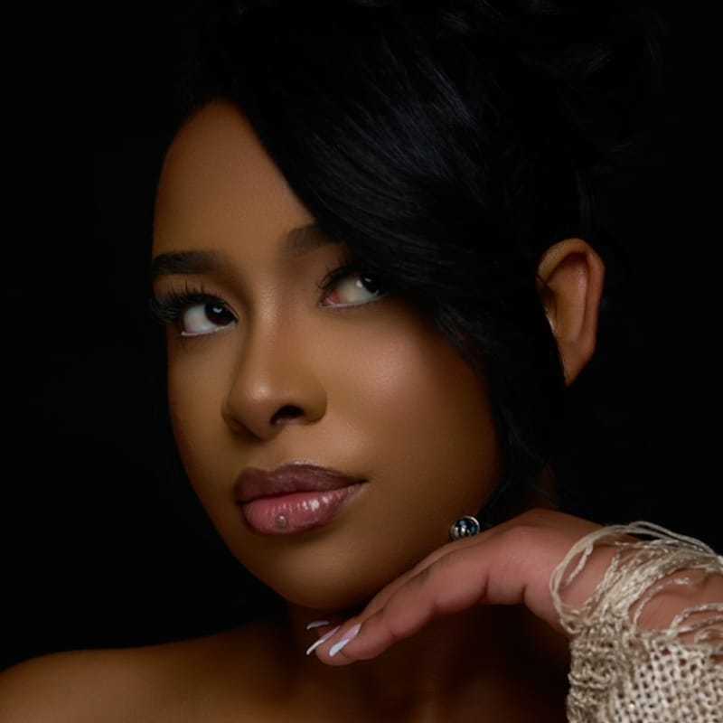 Portrait of Benilde, a professional stylist at Revolutions Salon, showcasing their expertise and style.